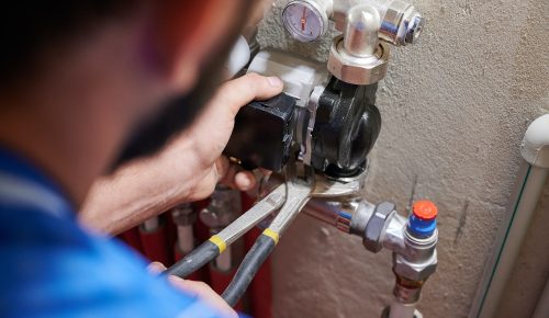 Male plumber installing heating radiator in apartment.